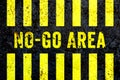 Ã¢â¬ÅNo-Go AreaÃ¢â¬Â warning sign in yellow letters painted on grungy concrete wall with yellow stripes.